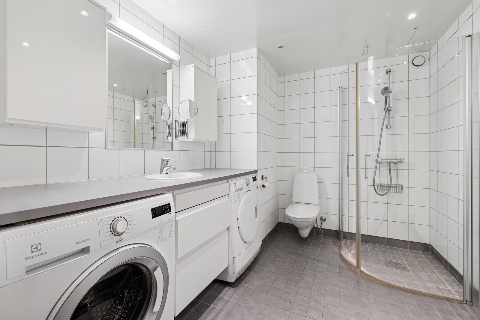 Badet kan by på flislagte vegger og gulv med gulvvarme. Her får du et vegghengt servantskap med plass til vaskemaskin og tørketrommel under. Galleribilde