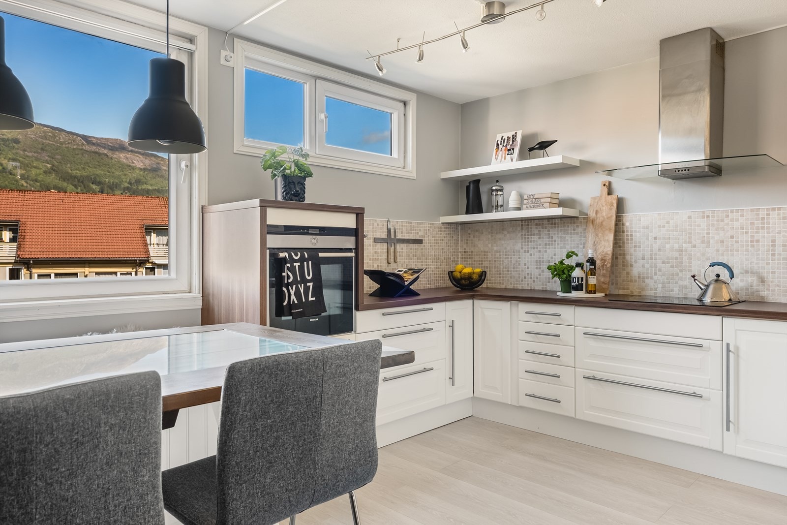 Lyst, tidløst kjøkken med profilerte fronter, glasskap og laminat benkeplate. Flott utsikt mot Ulriken fra kjøkkenbordet! Galleribilde