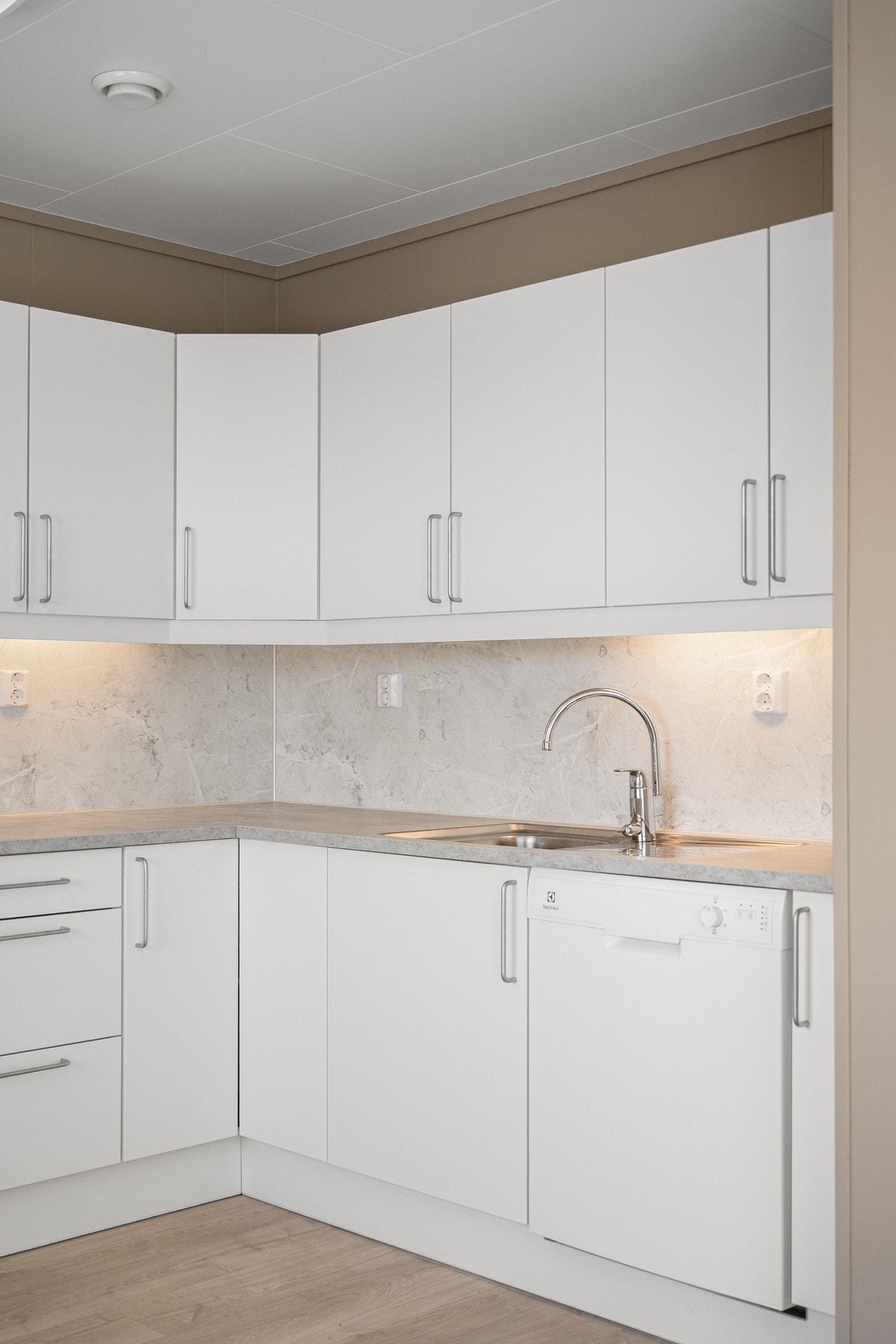 Lekkert kjøkken med lyse slette fronter og marmorfliser på veggen Galleribilde