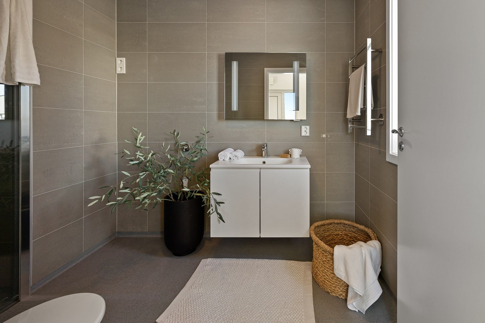 Stilrent bad med moderne innredning, dusjløsning og opplegg for vaskemaskin. Galleribilde