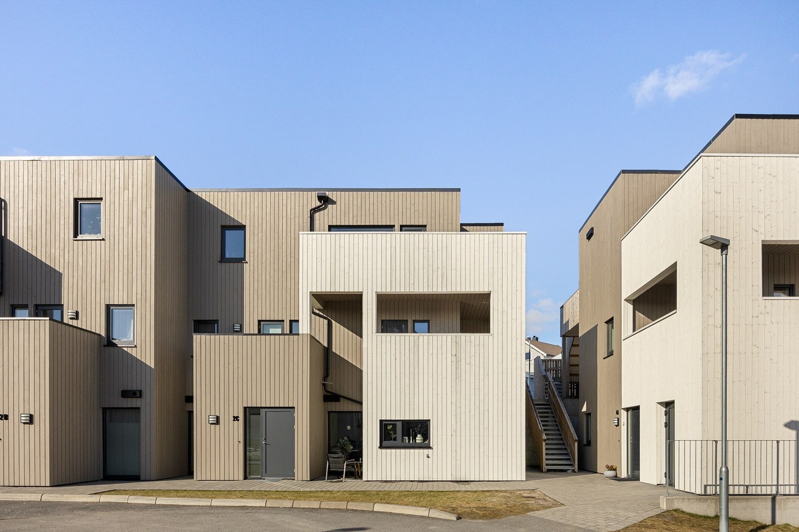 Tomteveien 2F - en moderne og stilren bygning med kubiske former, liggende panel og subtile detaljer som skaper et innbydende uttrykk i harmoni med omgivelsene. Galleribilde