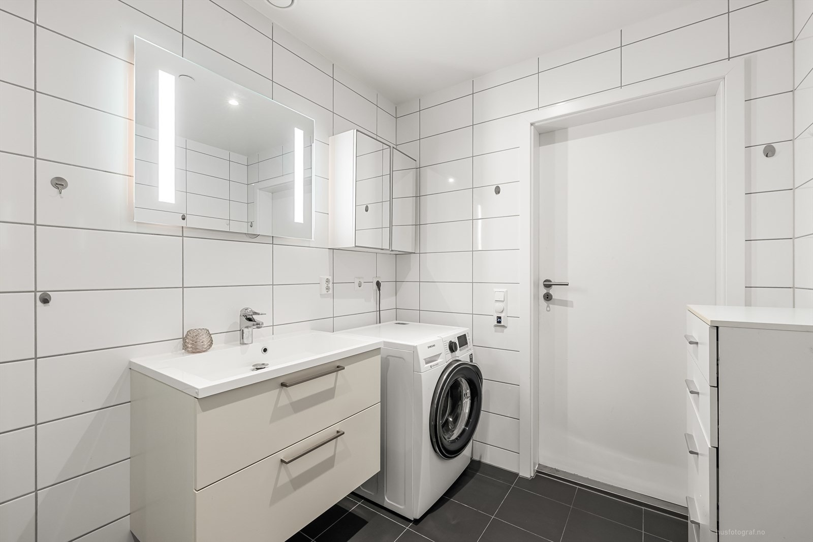 Badet har moderne innredning, med servant, dusjhjørne, vegghengt toalett og opplegg til vaskemaskin. Galleribilde