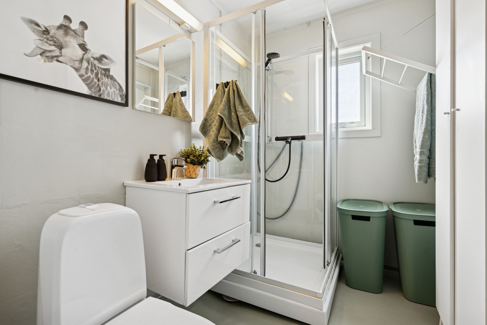 Badet har dusjkabinett, servant i innredning og gulvstående toalett. Galleribilde