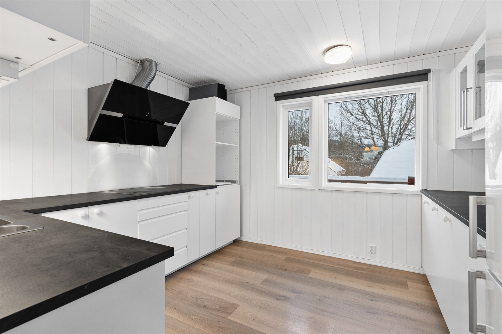 Kjøkkeninnredning fra ukjent årstall med glatte fronter. Laminerte benkeplater. Nedsenket oppvaskkum med ett-greps armatur. Stikkontakter og belysning over benk. Oppvaskmaskin, platetopp. Komfyrvakt tilkoblet. Galleribilde