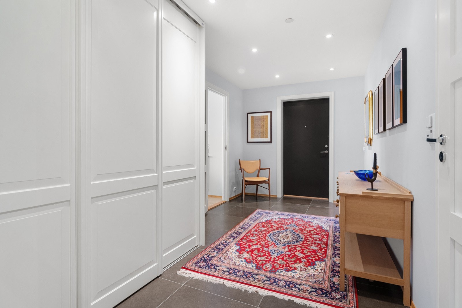 Enkel heisadkomst fra garasje til leilighetsplan og leiligheten har en innbydende hall med grå storformatfliser på gulvet og downlights i himlingen. Galleribilde