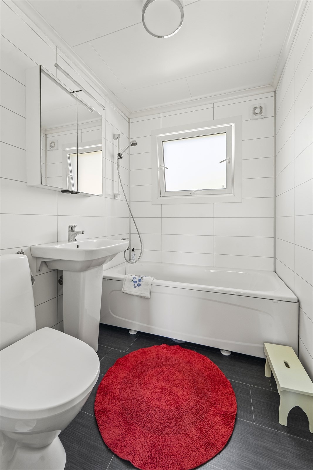 Pent bad med belegg på gulv og baderomsplater på vegg. Rommet er innredet med servant med speilskap, toalett og badekar. Badet ble oppgradet i 2019. Galleribilde