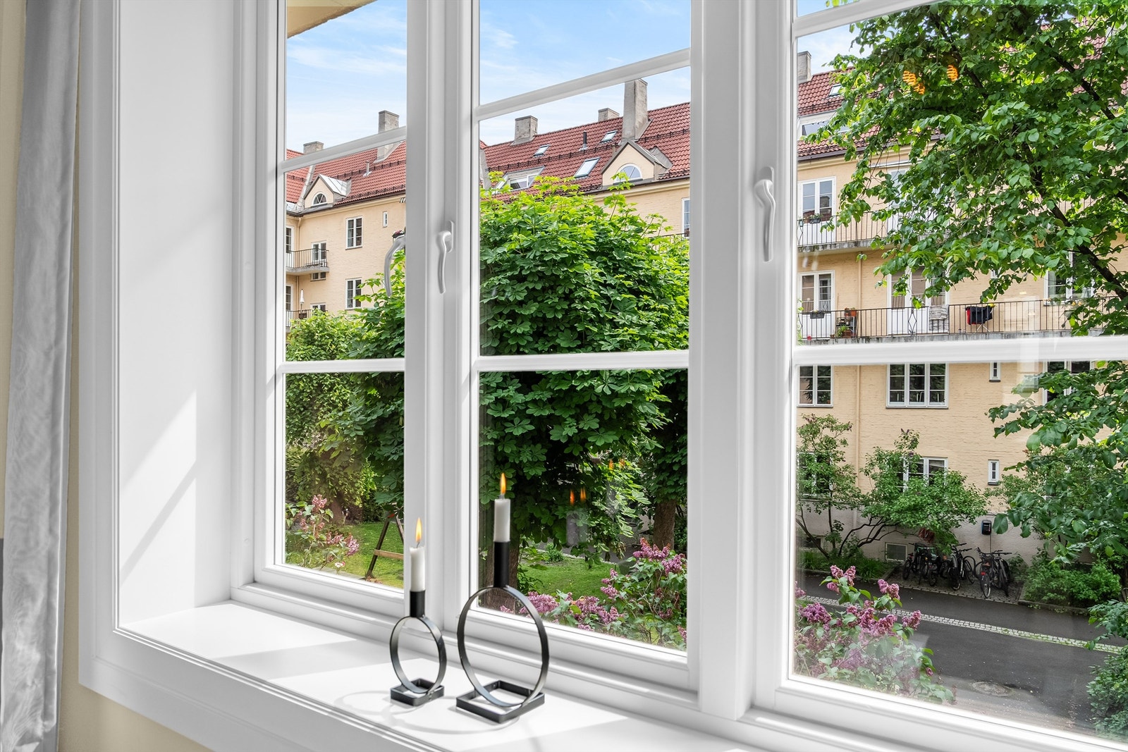 Utsikt fra stue til rolig og frodig bakgård. Galleribilde