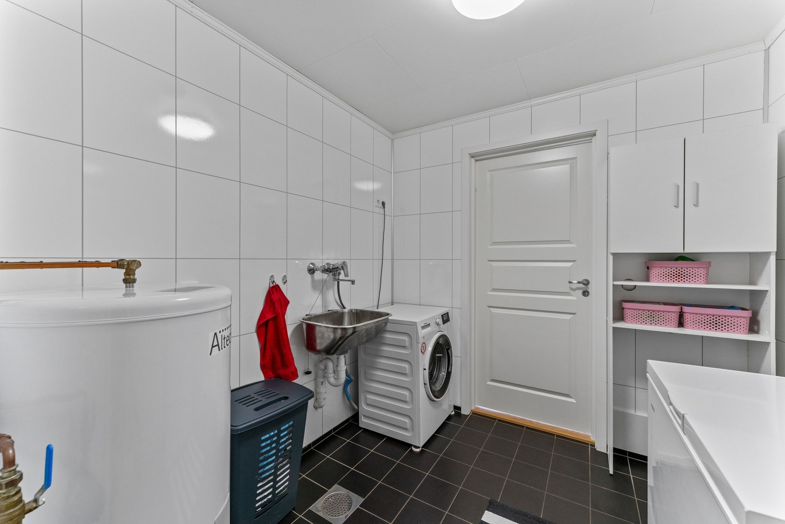 Praktisk vaskerom som er utstyrt med vaskemaskin og utslagsvask, og god plass til oppbevaring. Galleribilde