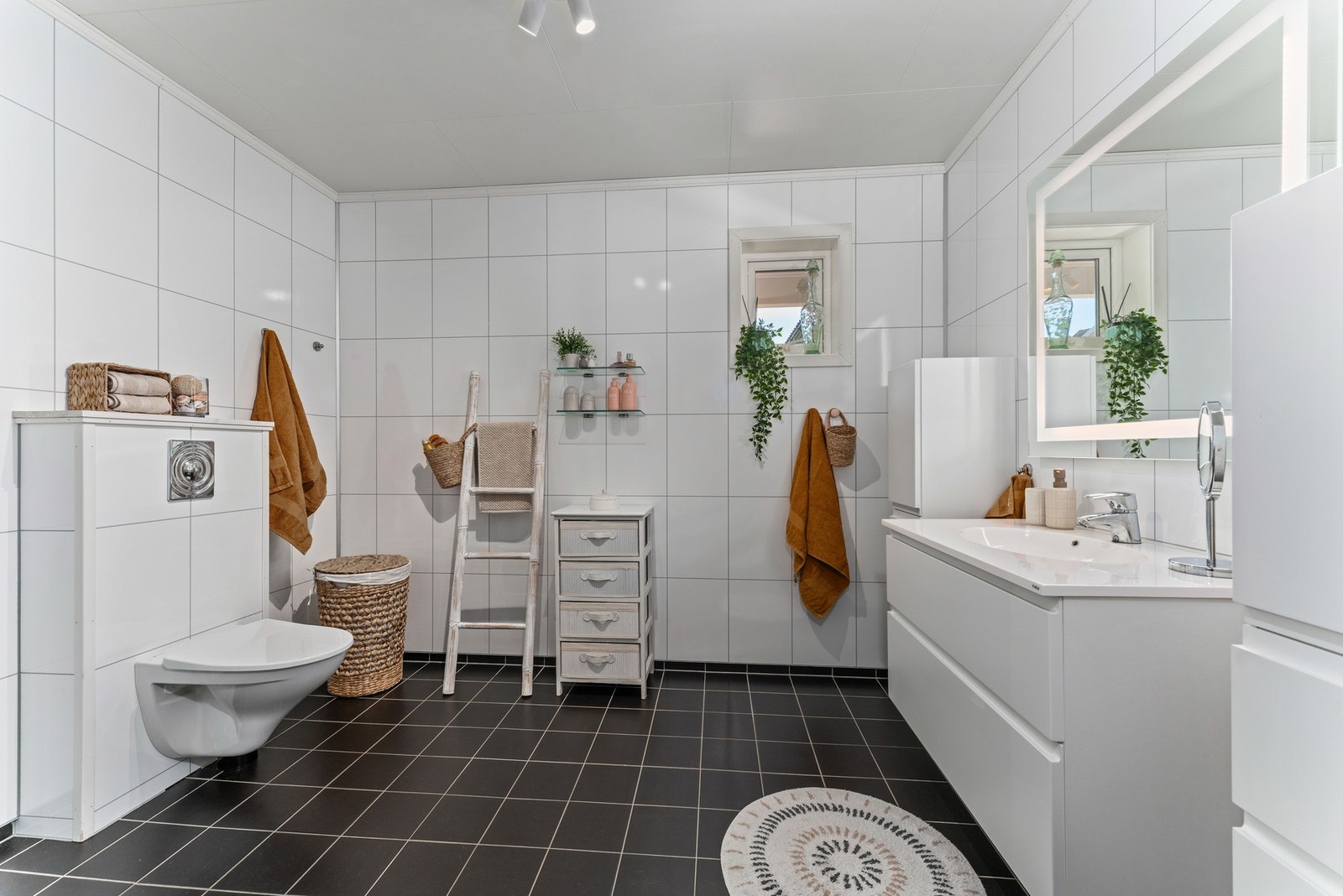 Delikat og romslig bad med flislagt gulv, dusjhjørne med glassvegger, toalett og moderne servant med underskap. Galleribilde