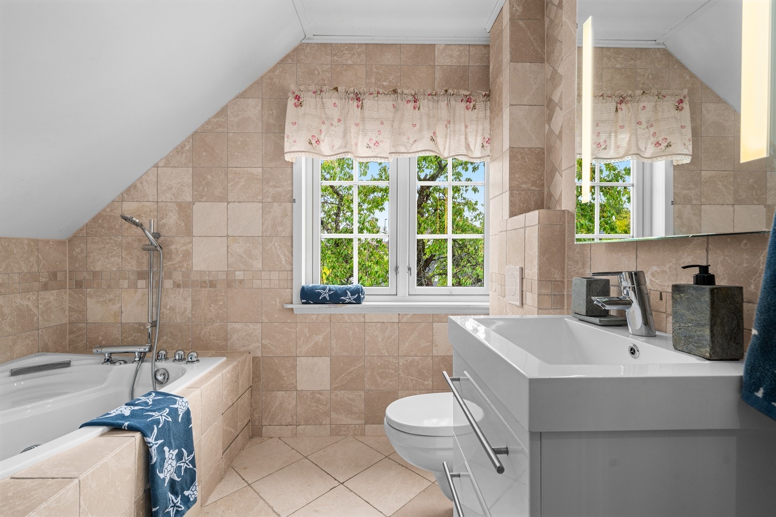 Flislagt bad med innfelt servant, vegghengt toalett og avslappende badekar. Galleribilde