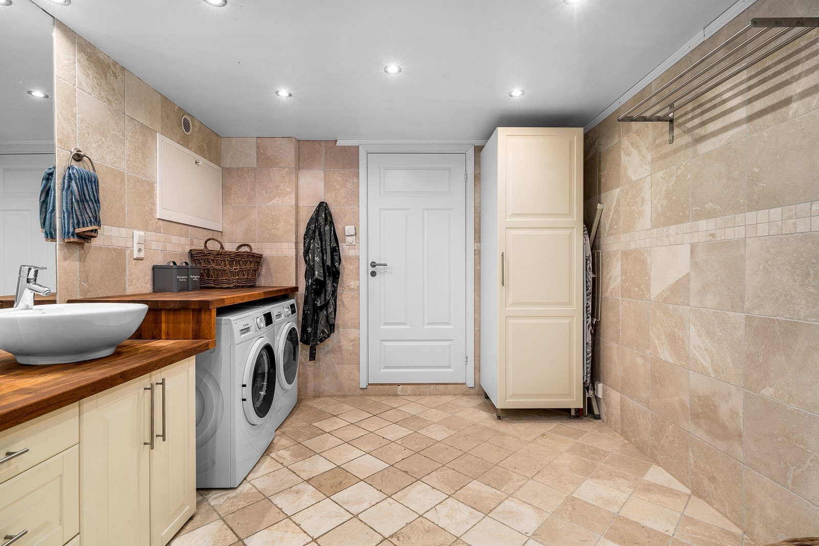 Romslig bad/vaskerom i kjeller med fliser, vannbåren varme og rikelig oppbevaringsløsninger. Galleribilde