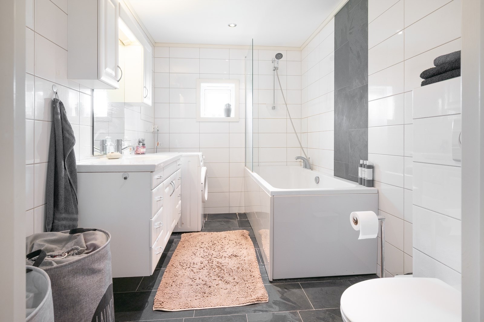 Helfliset bad/vaskerom med varmekabler, vegghengt wc og badekar med dusj Galleribilde