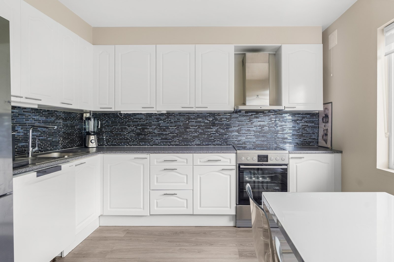 Leilighetens kjøkken er svært pent med tidløse fliser på vegg. Galleribilde