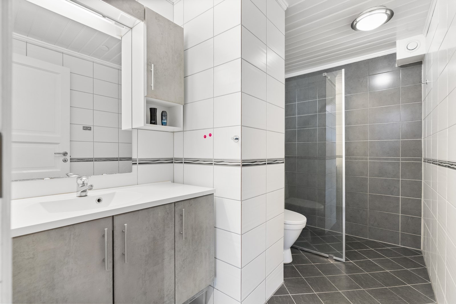 Delikat og lekkert flislagt bad med god oppbevaringsplass i servantinnredningen. Galleribilde