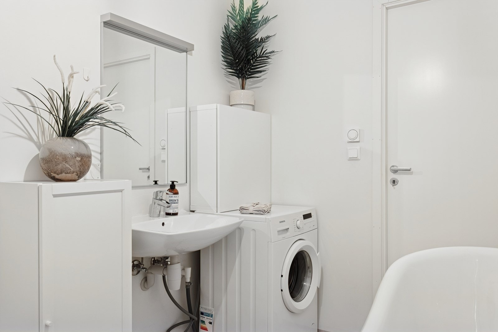 Baderommet/vaskerom er innredet med servant, dusjhjørne med glassvegger, vegghengt toalett, opplegg for vaskemaskin og badekar. Galleribilde