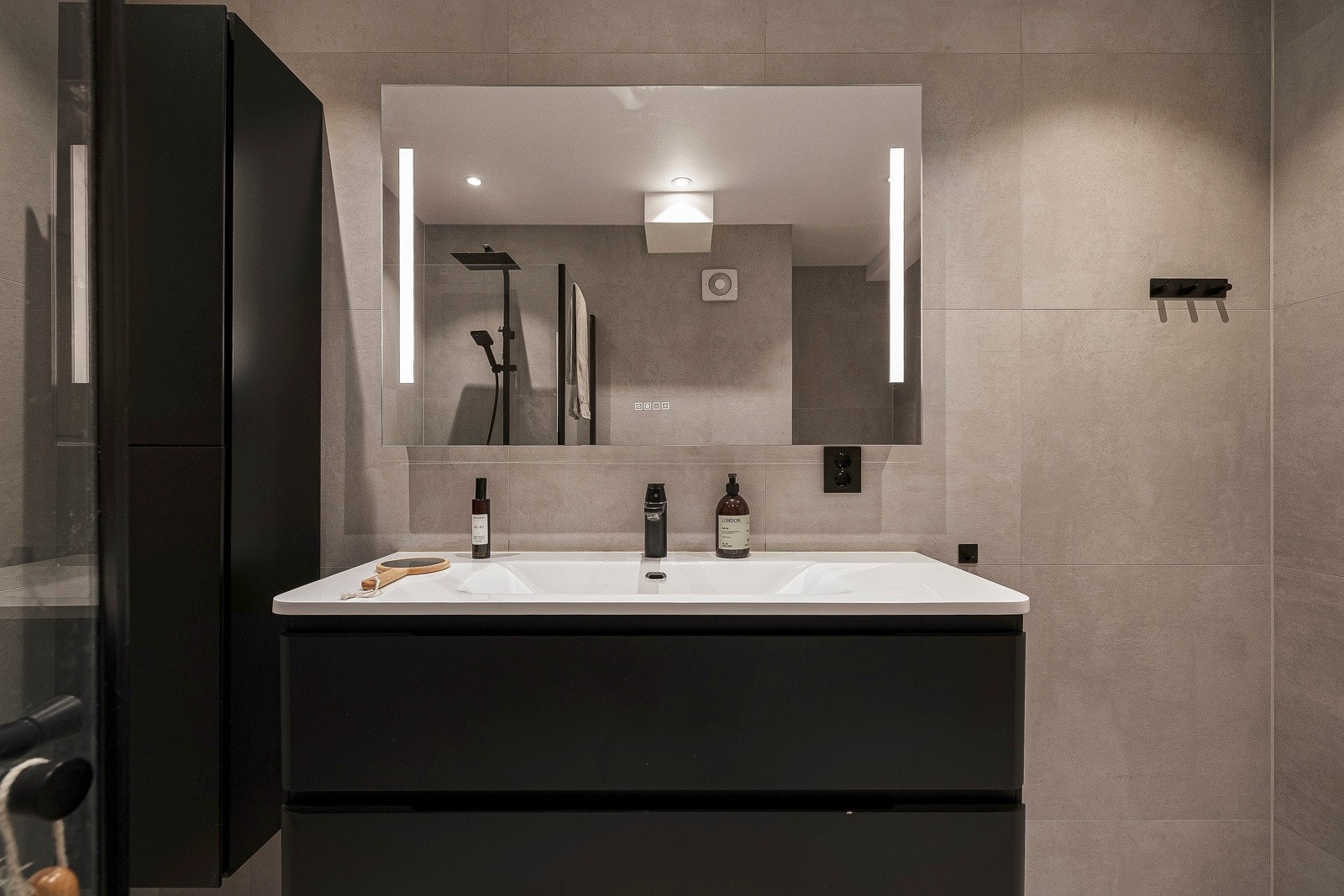 Badet inneholder baderomsinnredning med nedfelt servant, vegghengt toalett, dusjhjørne og oppheng for vaskemaskin. Galleribilde