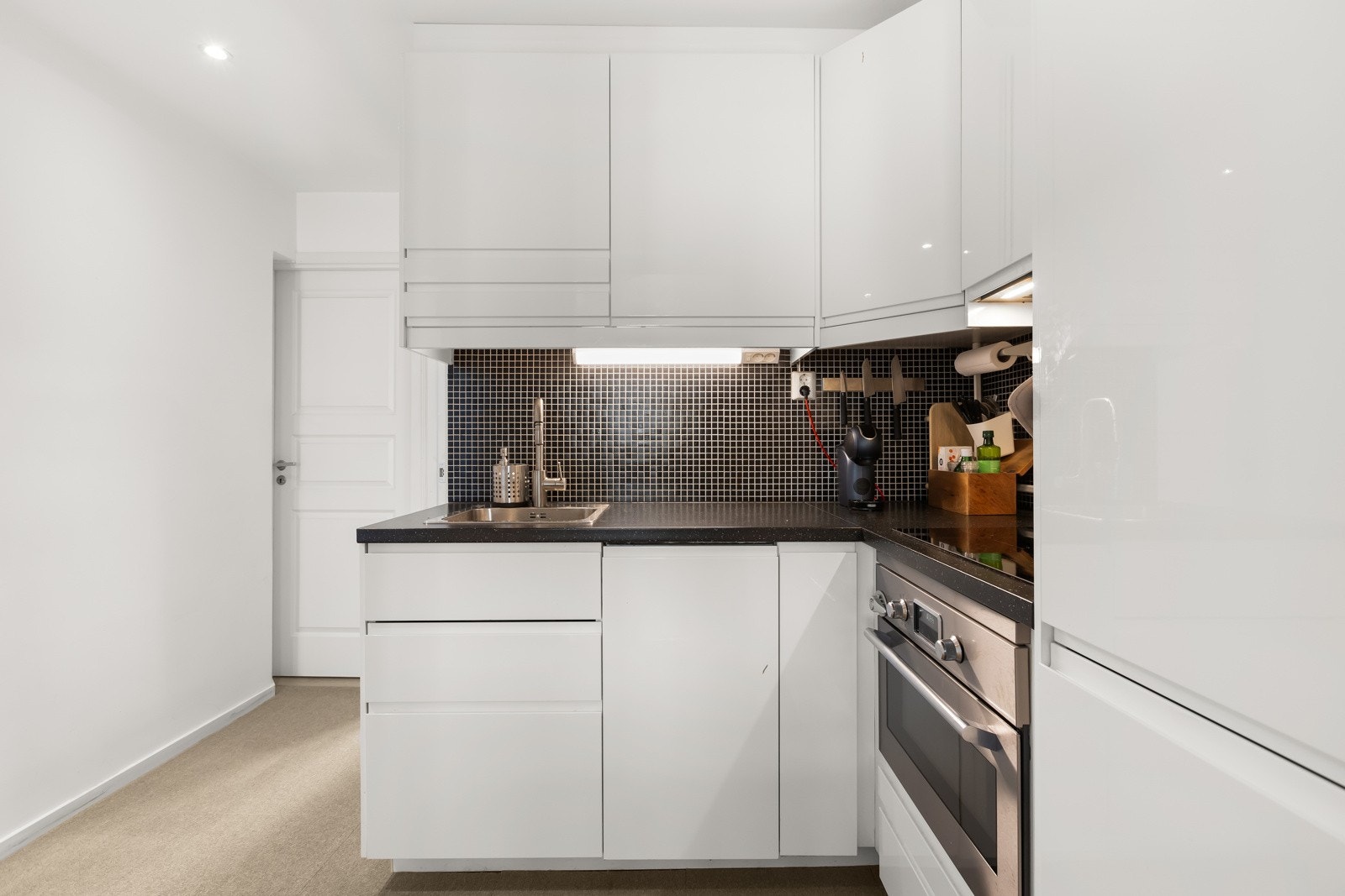 Kjøkkenet er smart plassert i åpen løsning mot stuen, noe som skaper en sosial atmosfære perfekt for både hverdagsliv og gjestemiddager Galleribilde