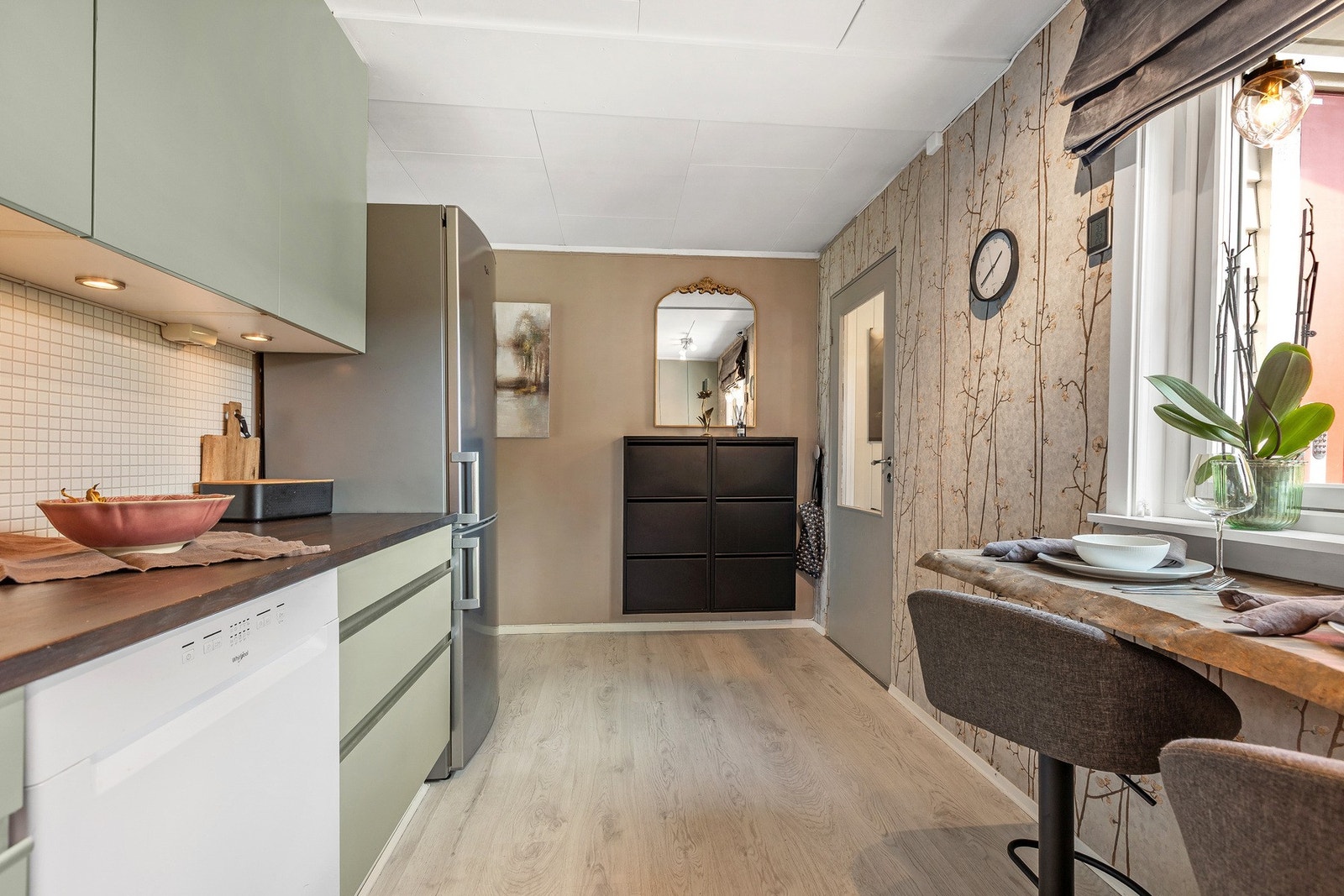 Kjøkkenet fremstår som pent og innbydende med moderne tapet på en vegg. Galleribilde