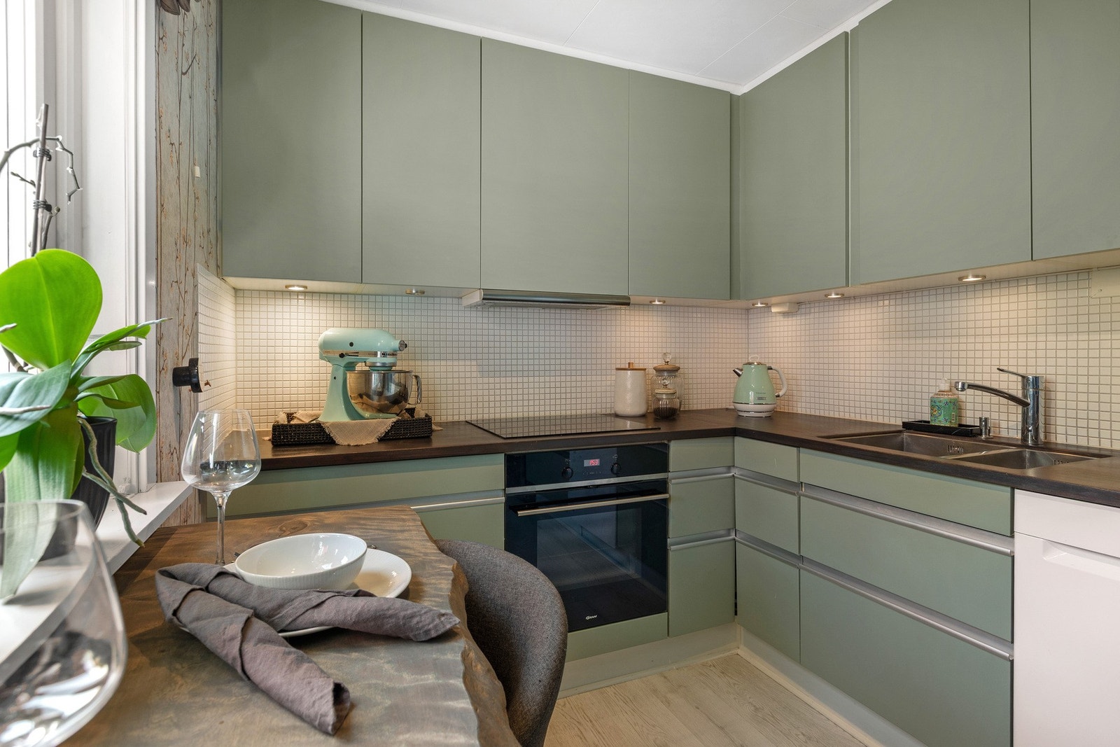 Innredningen har glatte overflater malt i en delikat grønnfarge og består av takhøye overskap og underskap. Galleribilde