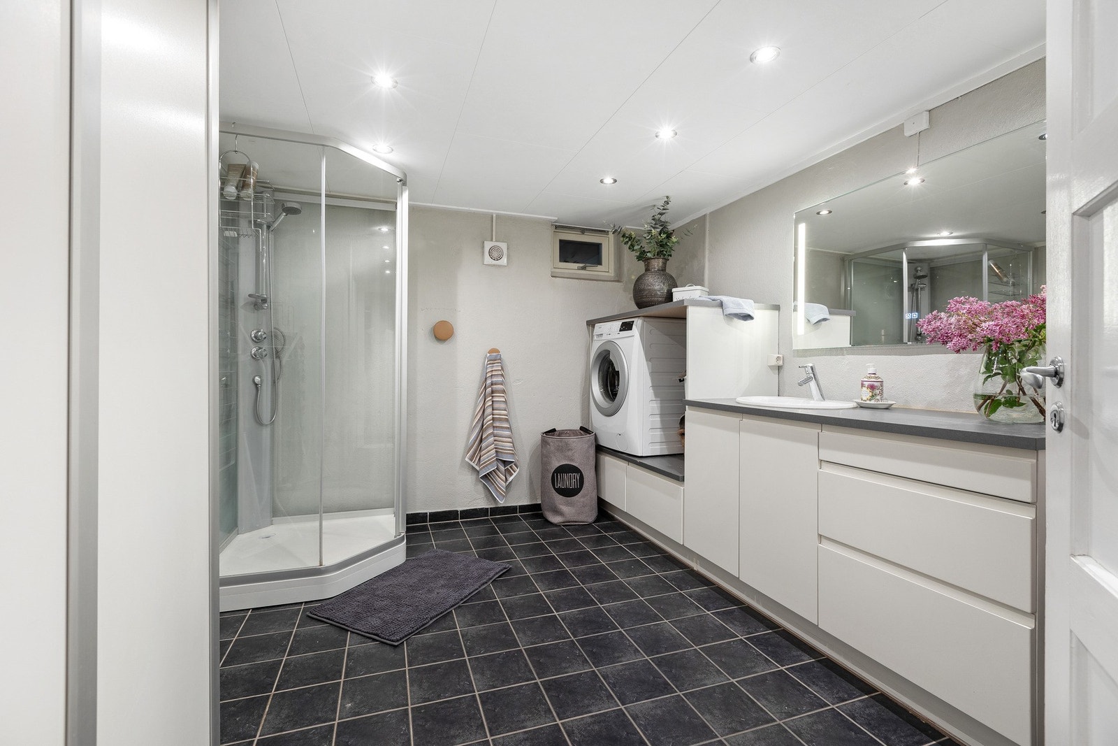 I kjelleretasjen finner man et innredet baderom, kombinert vaskerom med flislagte gulv og malt mur og plater på veggene. Galleribilde