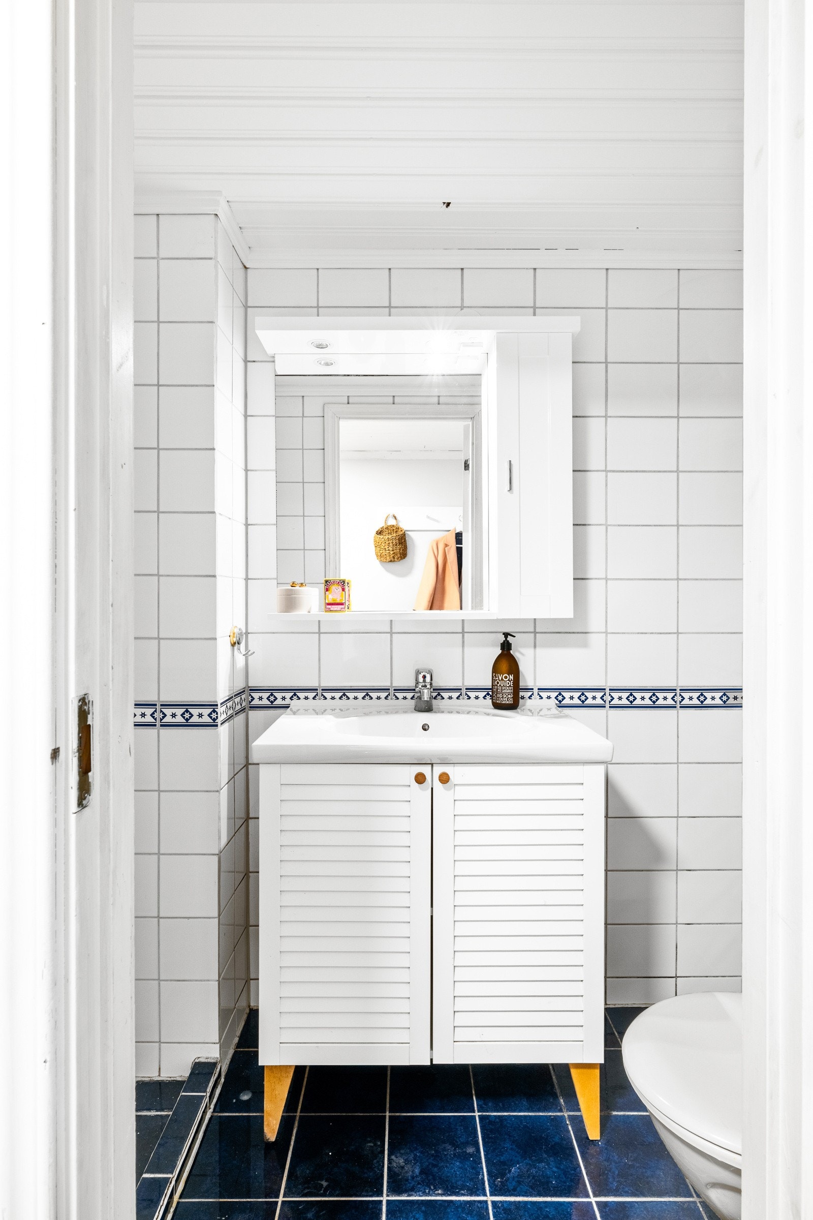 Badet underetasjen i har hvite fliser på veggene og blå fliser på gulv med sluk. Galleribilde