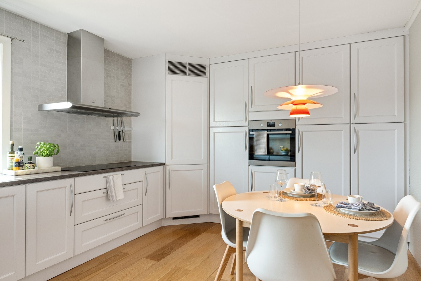 Innredningen fra Strai har lyse, profilerte fronter, vitrinedører, takhøye skap og grå laminatbenkeplate med planlimt kum med Quooker-kran. Galleribilde