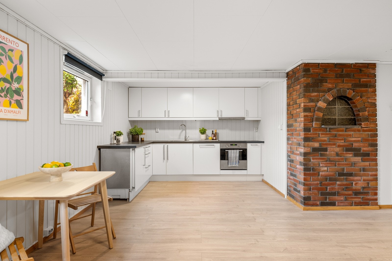 Kjøkkenet har et stilrent, pent design med god skap- og benkeplass. Innredningen fra 2010 har hvite, glatte fronter og mørk laminatbenkeplate med nedfelt kum i stål. Galleribilde