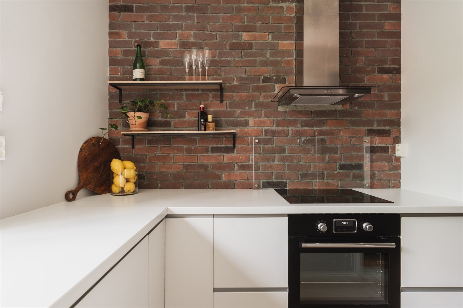 Lekkert kjøkken med glatte fronter, integrerte hvitevarer, downlights og stilren avtrekksvifte. Appstyrt varmefolie i gulvet Galleribilde