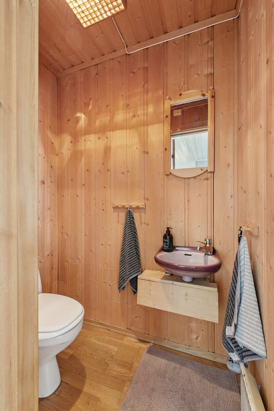 Toalettrom i første etasje har parkett på gulv og panel på vegger. Rommet er utstyrt med gulvmontert toalett og servant. Galleribilde