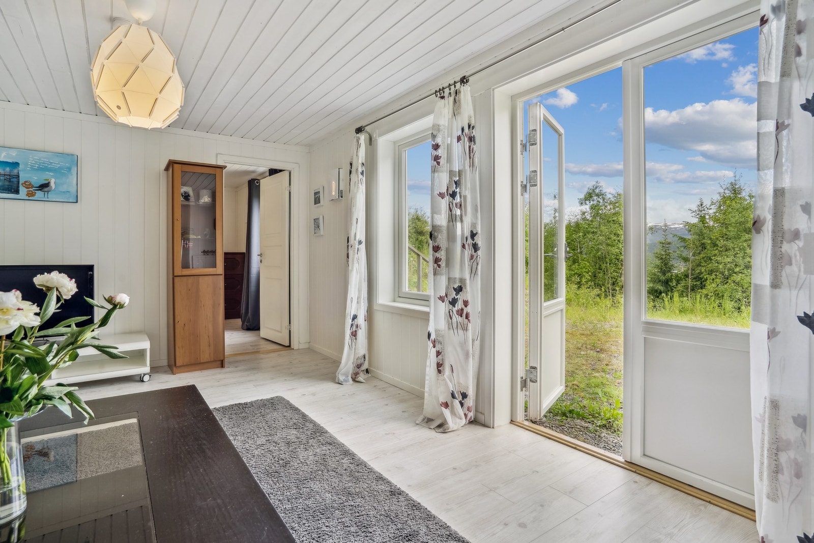 Rommet har store vinduer og direkte utgang til det grønne uteområdet på husets bakside. Galleribilde