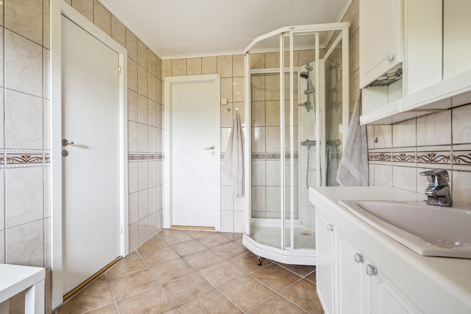 Badet i første etasje har fliser på gulv og vegger, samt dusjkabinett og varmekabler. Galleribilde