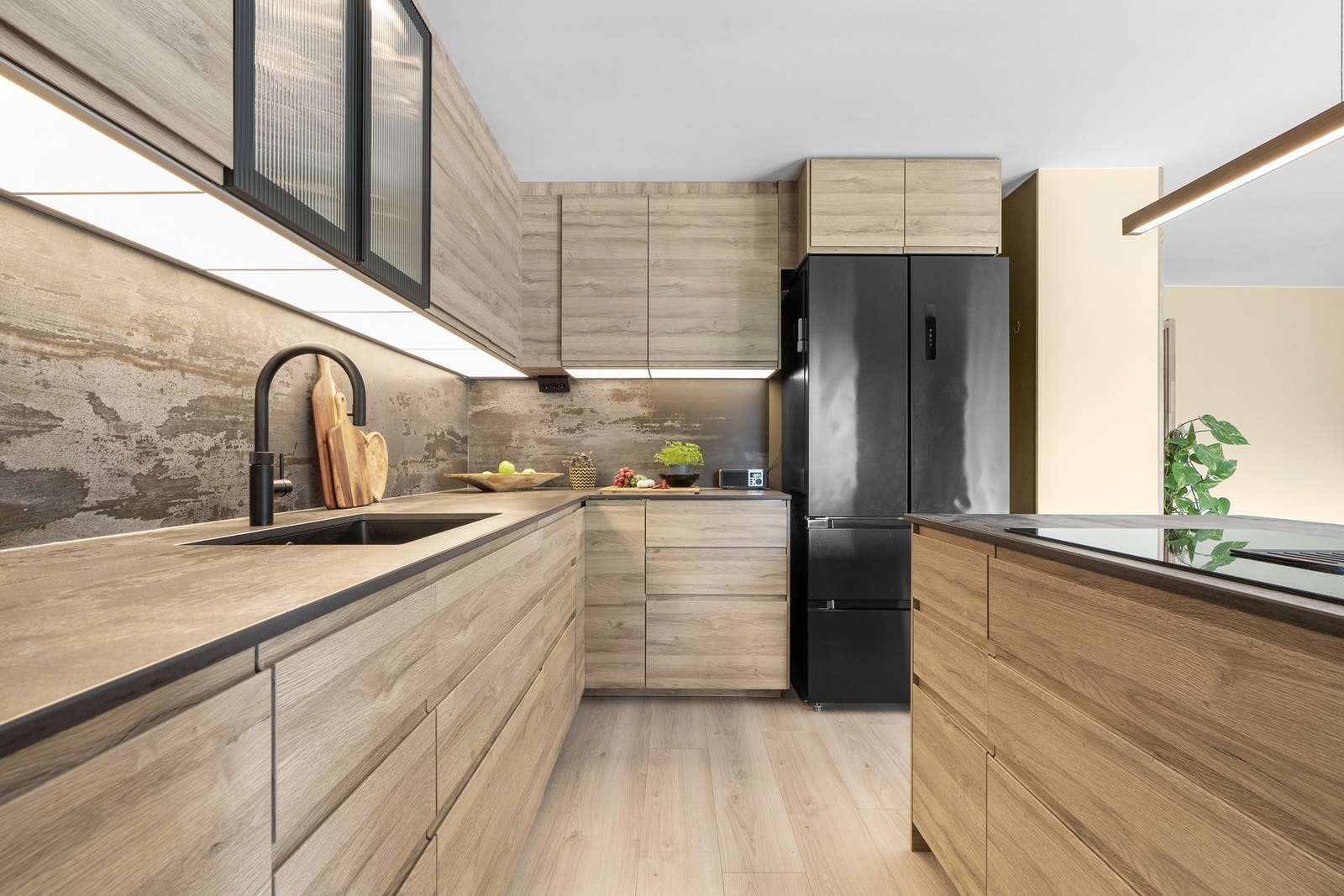 Stilig kjøkkeninnredning; med glatte fronter og keramisk benkeplate, med nedfelt kum i kompositt. Samme type plate er benyttet som backsplash på veggen over benken, og gir et pent helhetsinntrykk. Galleribilde