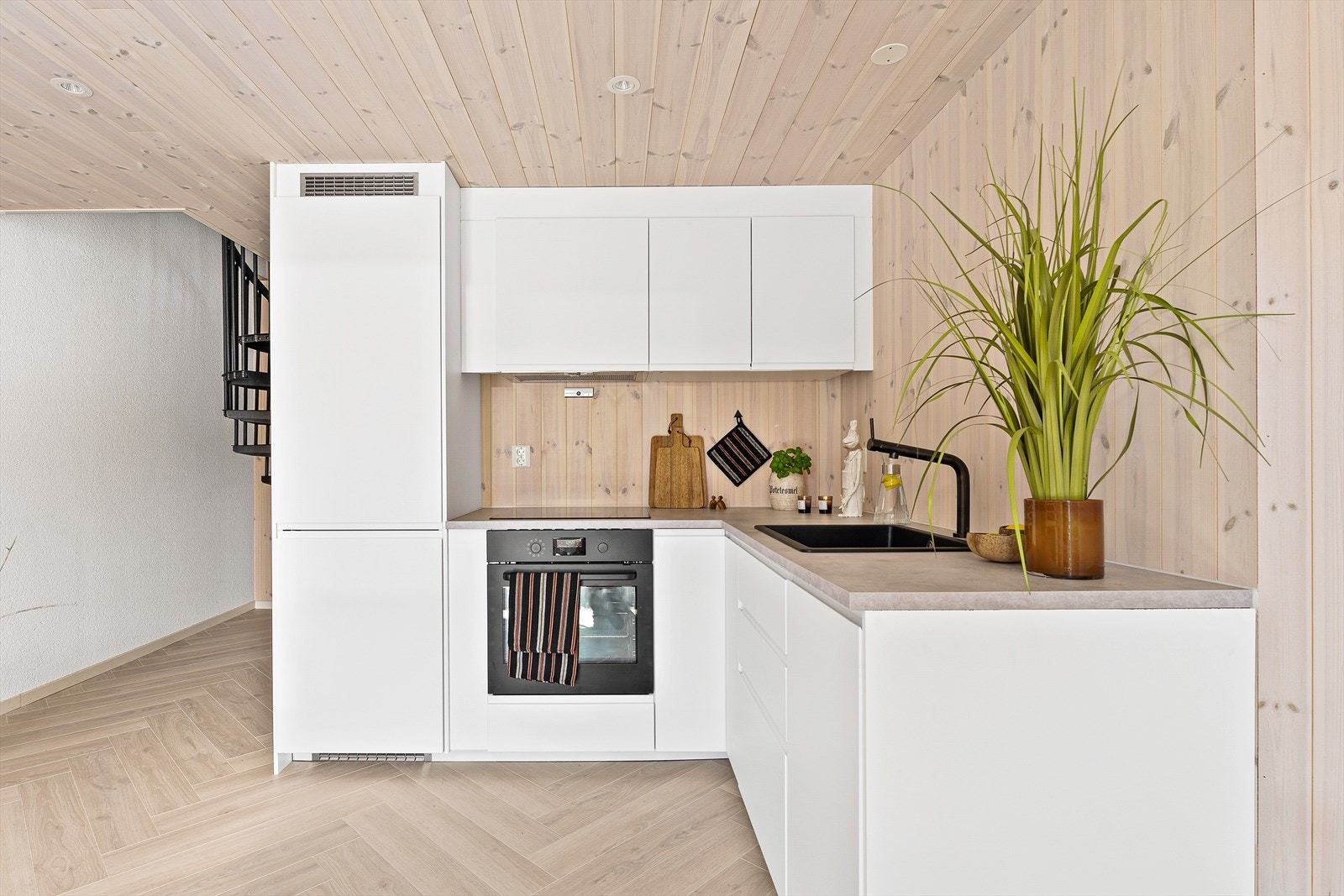 Kjøkkenet er utstyrt med integrerte hvitevarer i form av kjøl/frys, stekeovn, induksjonstopp og oppvaskmaskin Galleribilde