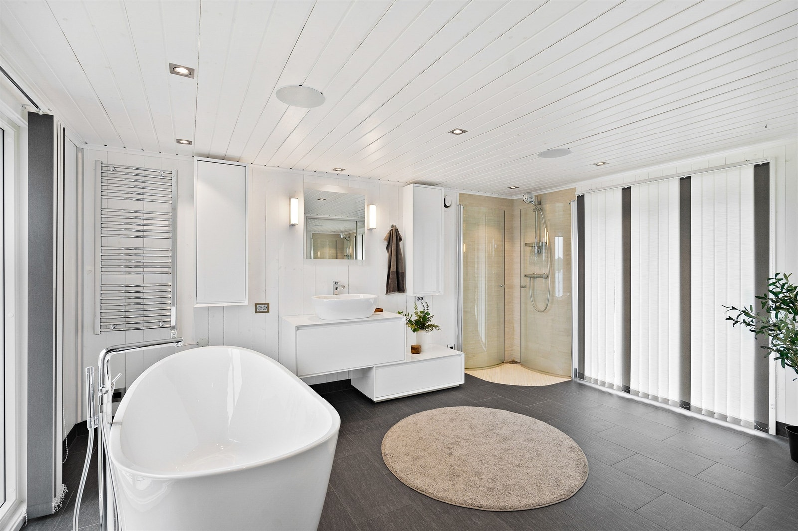 Badet inneholder servant med skap, susjhjørne, wc, badekar og opplegg til vaskemaskin bak egne skyvedører. Galleribilde