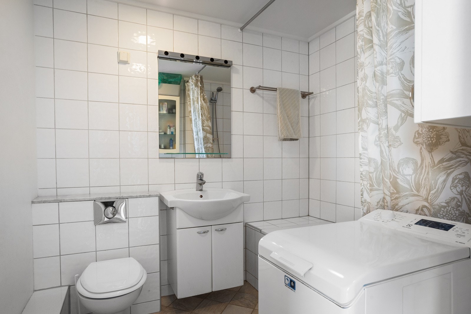 Badet har servantskap med glatte fronter og heldekkende servant med ettgreps blandebatteri. Det er vegghengt toalett med innebygd sisterne, samt innebygd badekar med veggmontert blandebatteri og hånddusj. I tillegg er det opplegg for vaskemaskin. Galleribilde