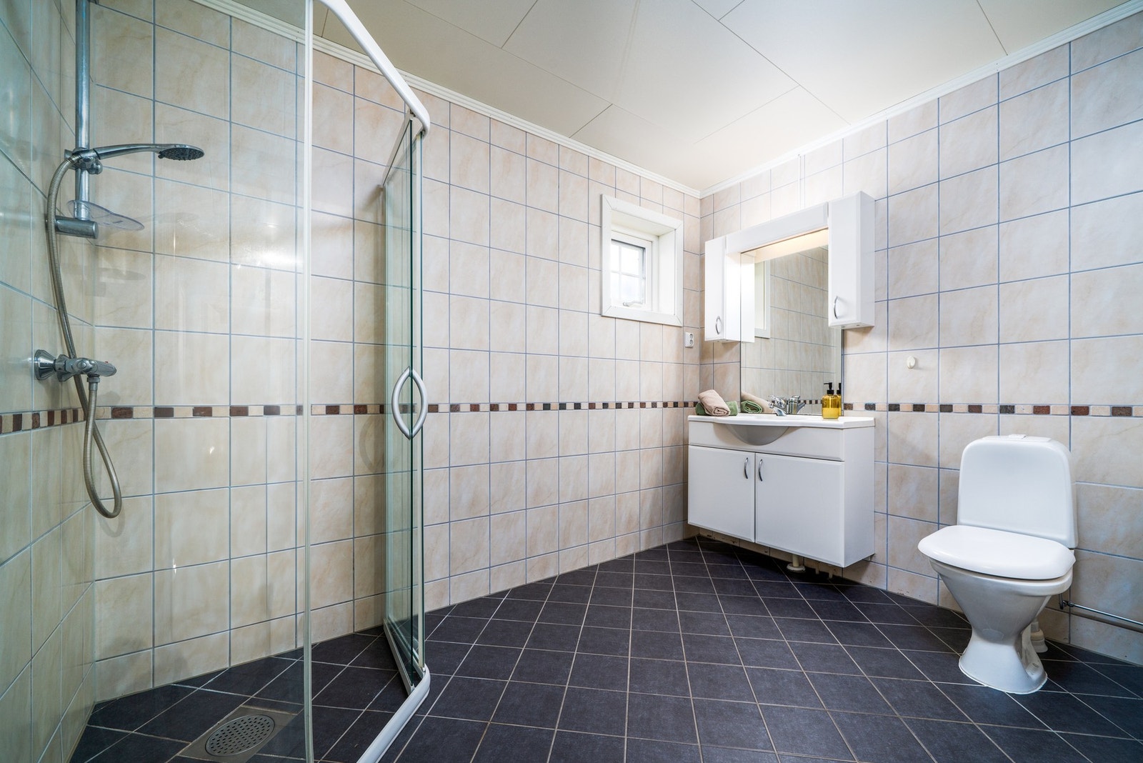 Badet har en praktisk dusjnisje med skyvedør. Det vegghengte servantskapet gir ekstra lagringsplass. Galleribilde