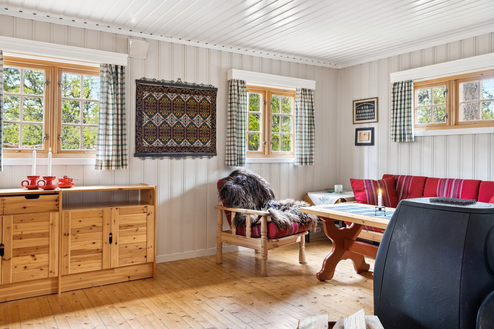 Stuen har lune trepaneler og store vinduer som skaper en innbydende atmosfære. Galleribilde