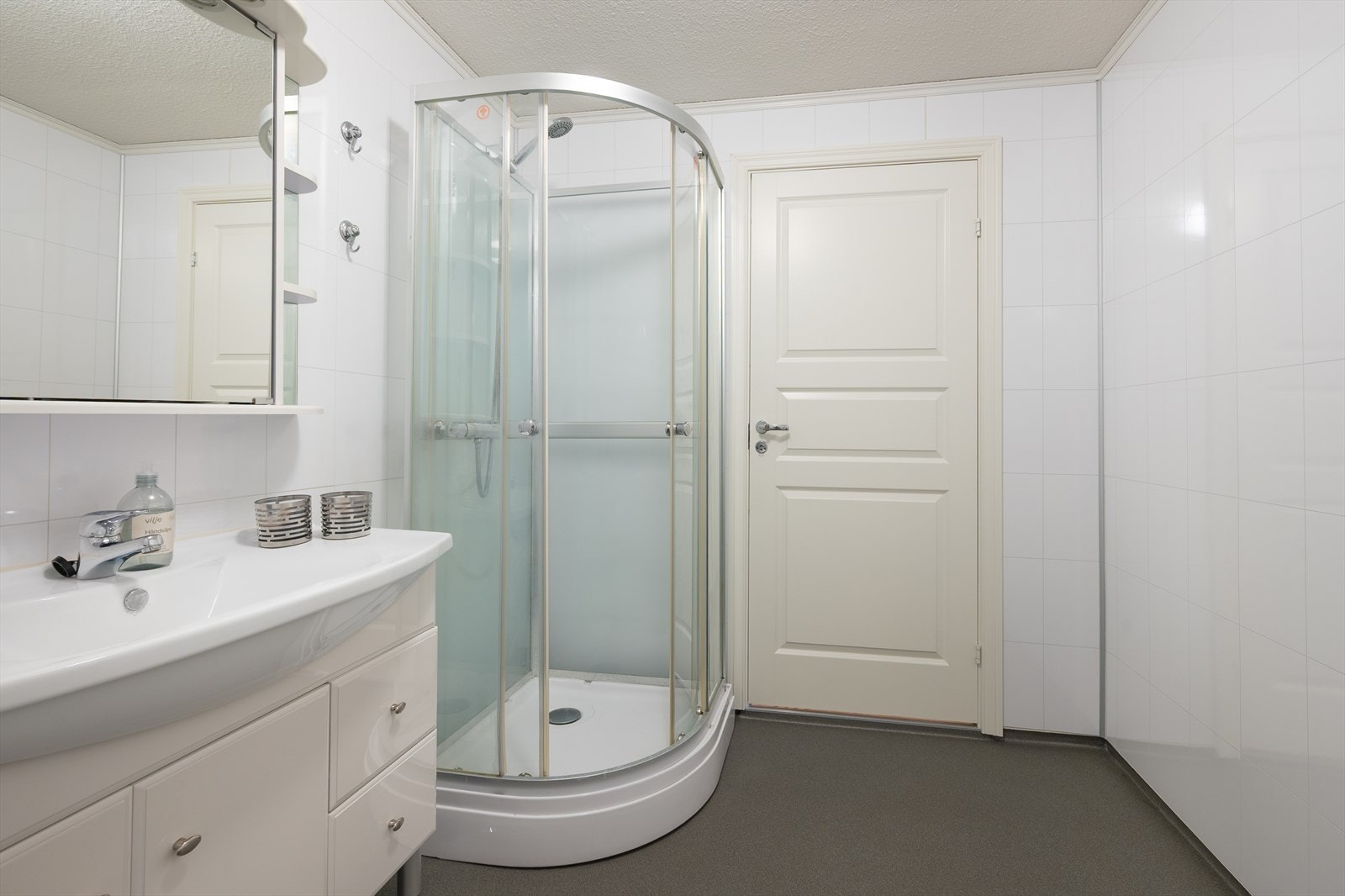 Badet er utstyrt med dusjkabinett, heldekkende servant, wc og opplegg til vaskemaskin/tørketrommel Galleribilde