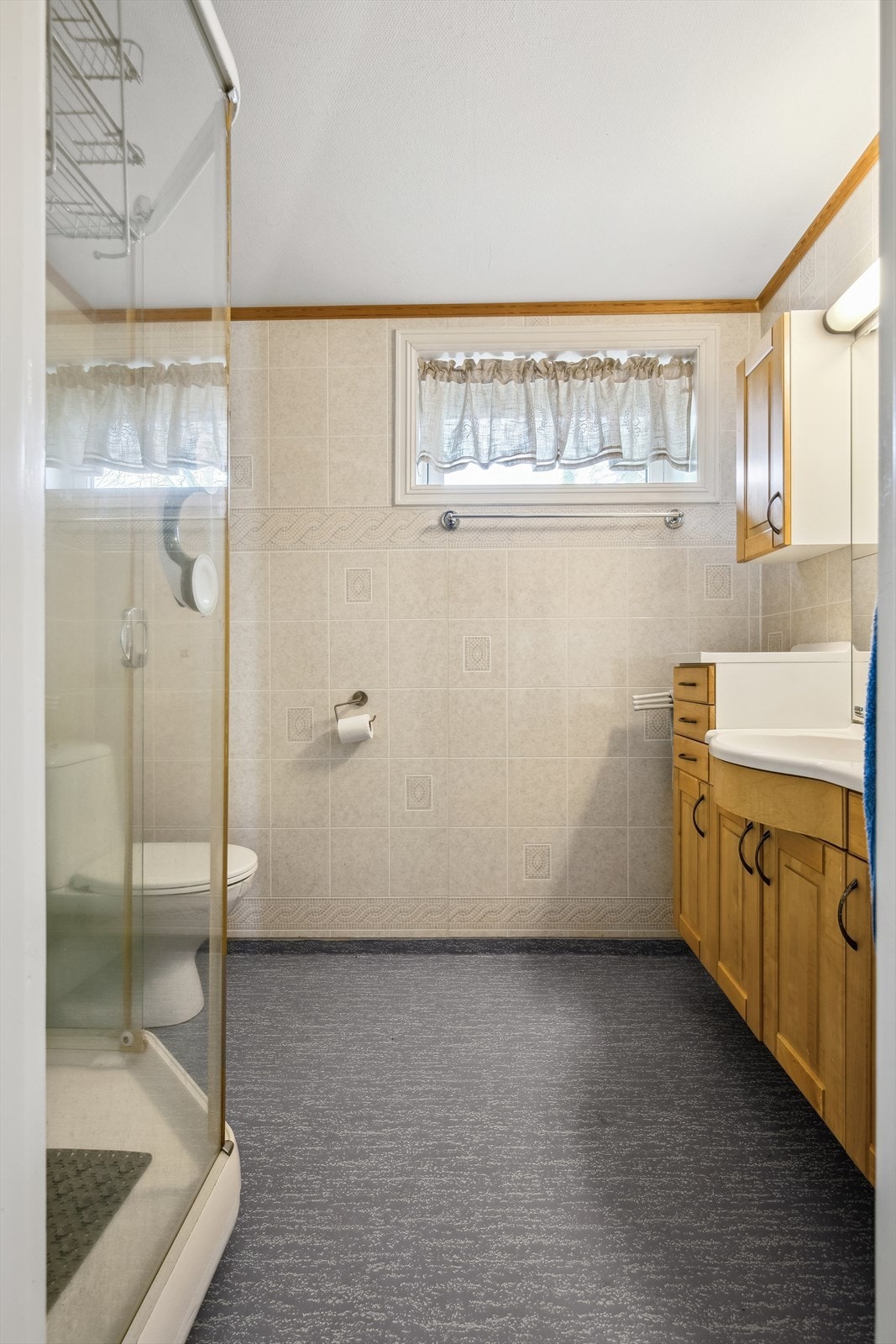 Badet har gulvstående toalett, servant i innredning og dusjkabinett. Galleribilde
