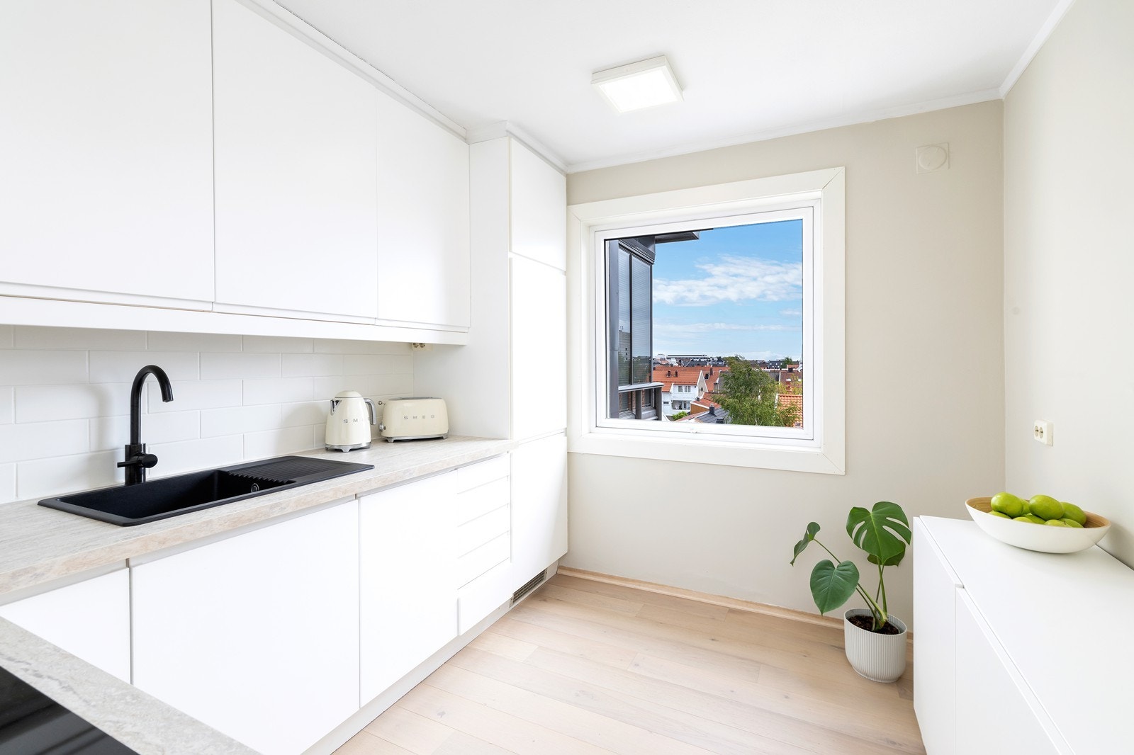 Pent kjøkken fra IKEA med hvite fronter og laminat benkeplate. Integrerte hvitevarer. Galleribilde