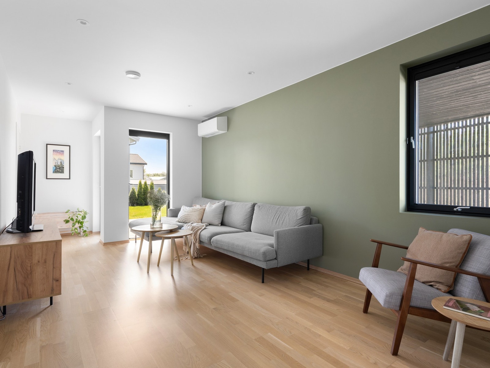 Romslig stue med parkett, lyse overflater og utgang til terrasse og hage Galleribilde