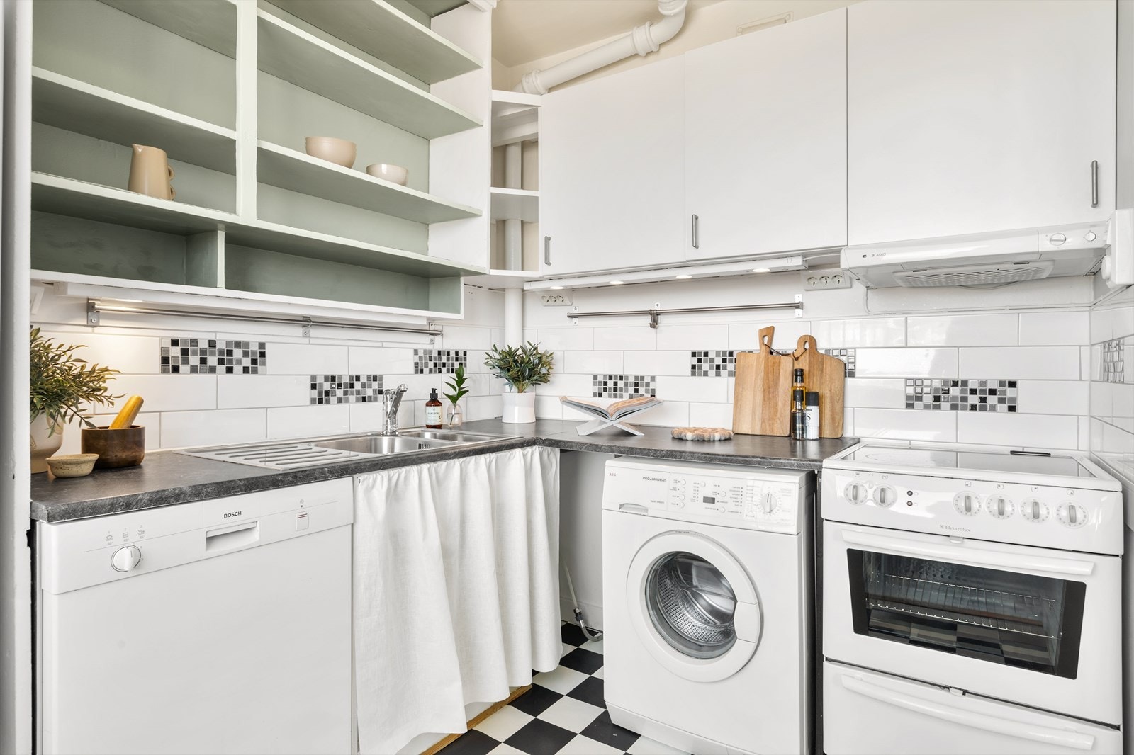 Kjøkkenet er utstyrt med en kombinasjon av overskap og åpne hyller. Det er plass til frittstående hvitevarer som komfyr, vaskemaskin, oppvaskmaskin og kjøl- og fryseskap. Galleribilde