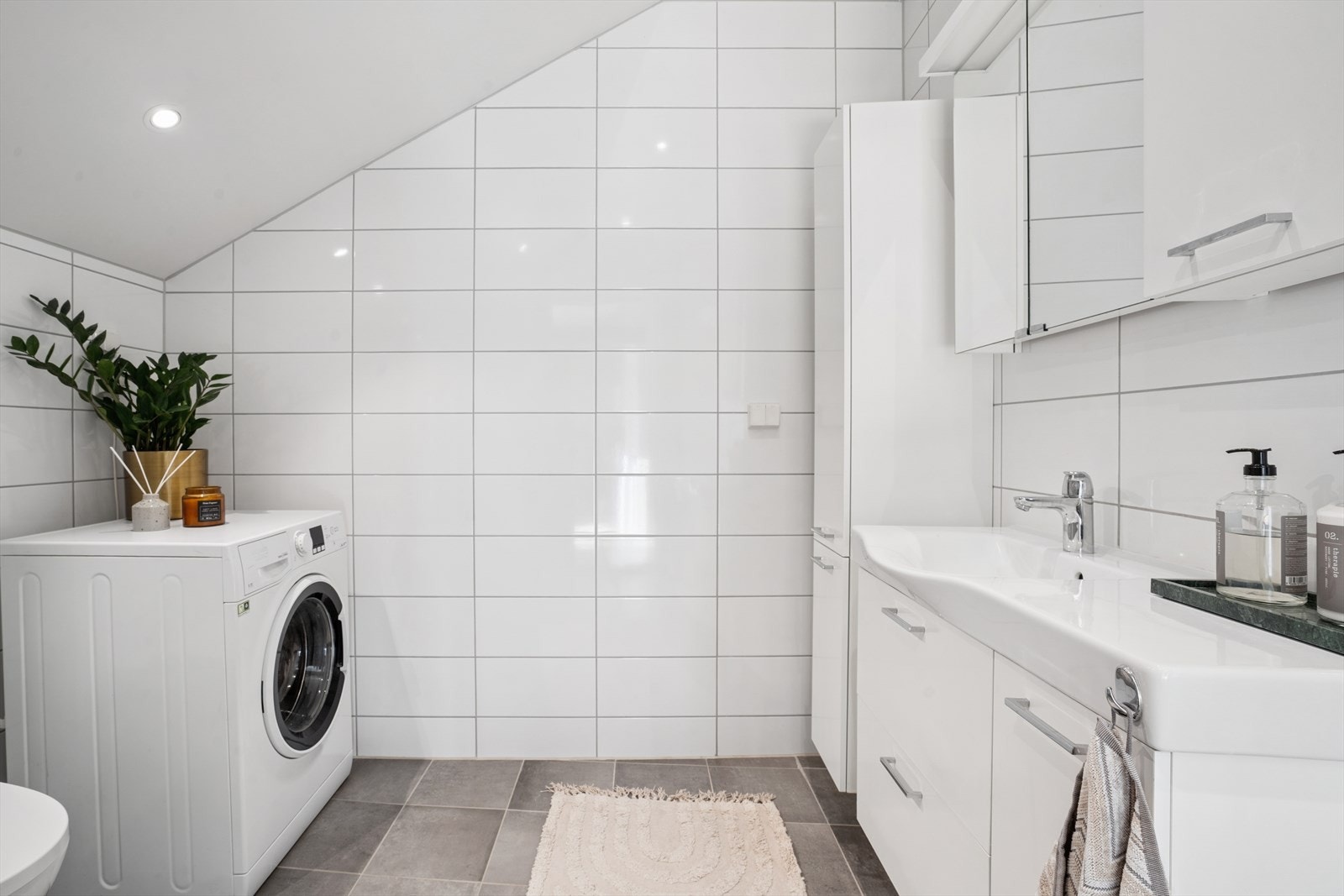 Baderommet er utstyrt med veggmontert WC, dusjplass med inn-utadslående dusjvegger, servant og opplegg for vaskemaskin. Galleribilde