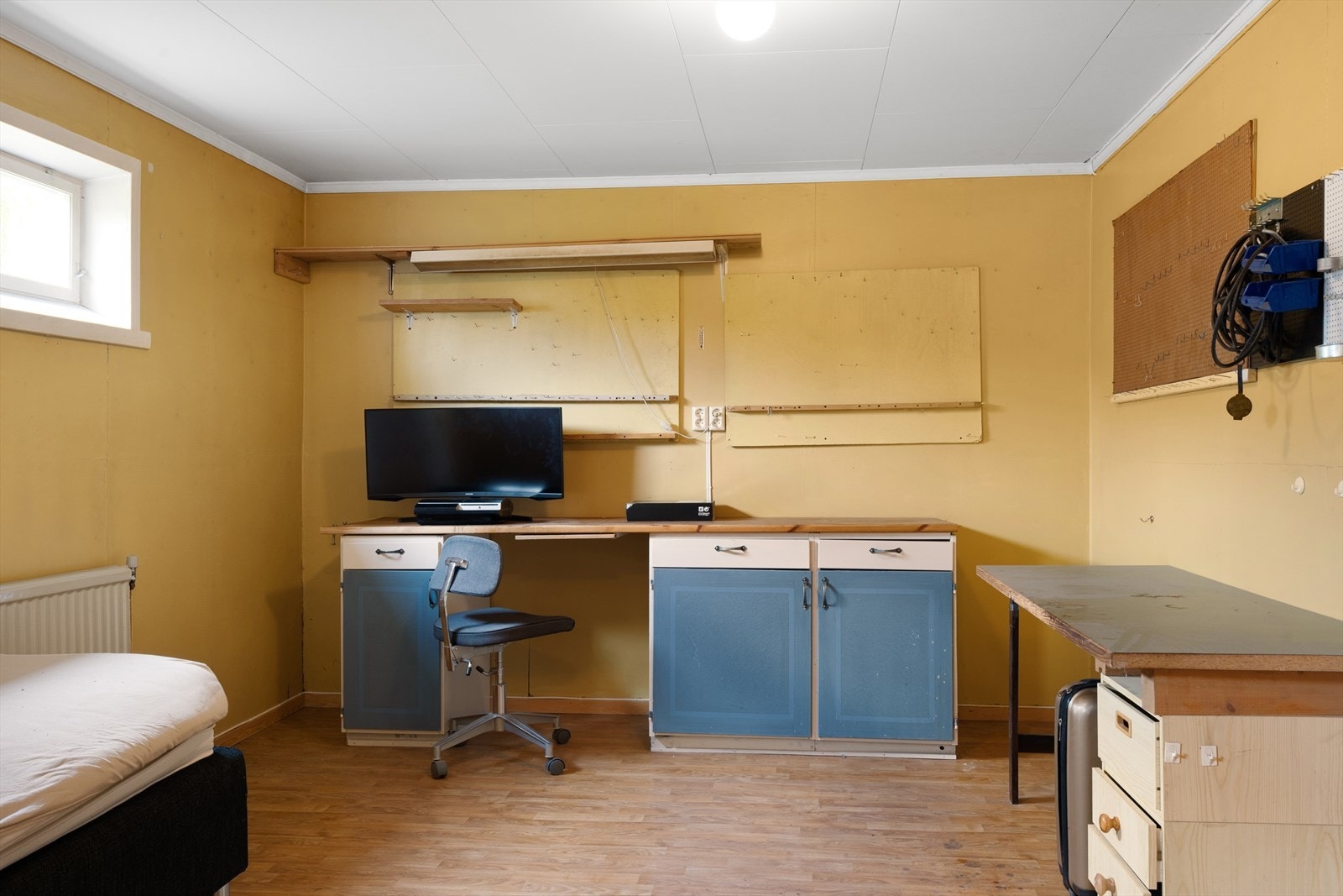 Ett av de øvrige rommene i kjelleretg. er innredet som hobbyrom m/kontorplass, kjøkkenbenk og seng. Galleribilde