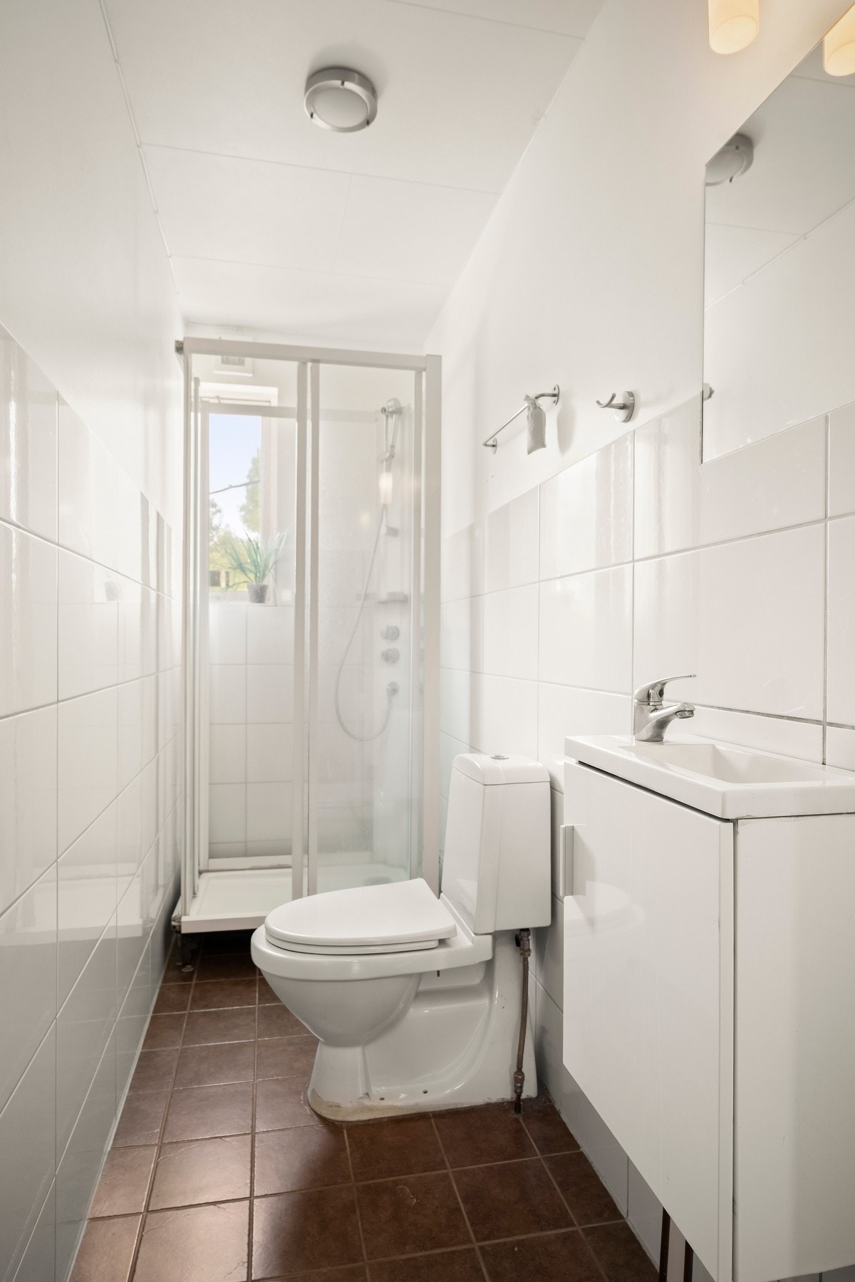 Rom benyttet som bad har flislagt gulv og vegger, og er innredet med servant med underskap, speil, dusjkabinett og toalett. Galleribilde