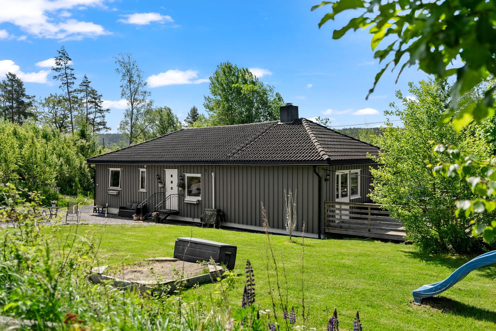 Tomten er romslig og opparbeidet med gressplen og beplantning, noe som gir gode leke- og oppholdsmuligheter. Galleribilde