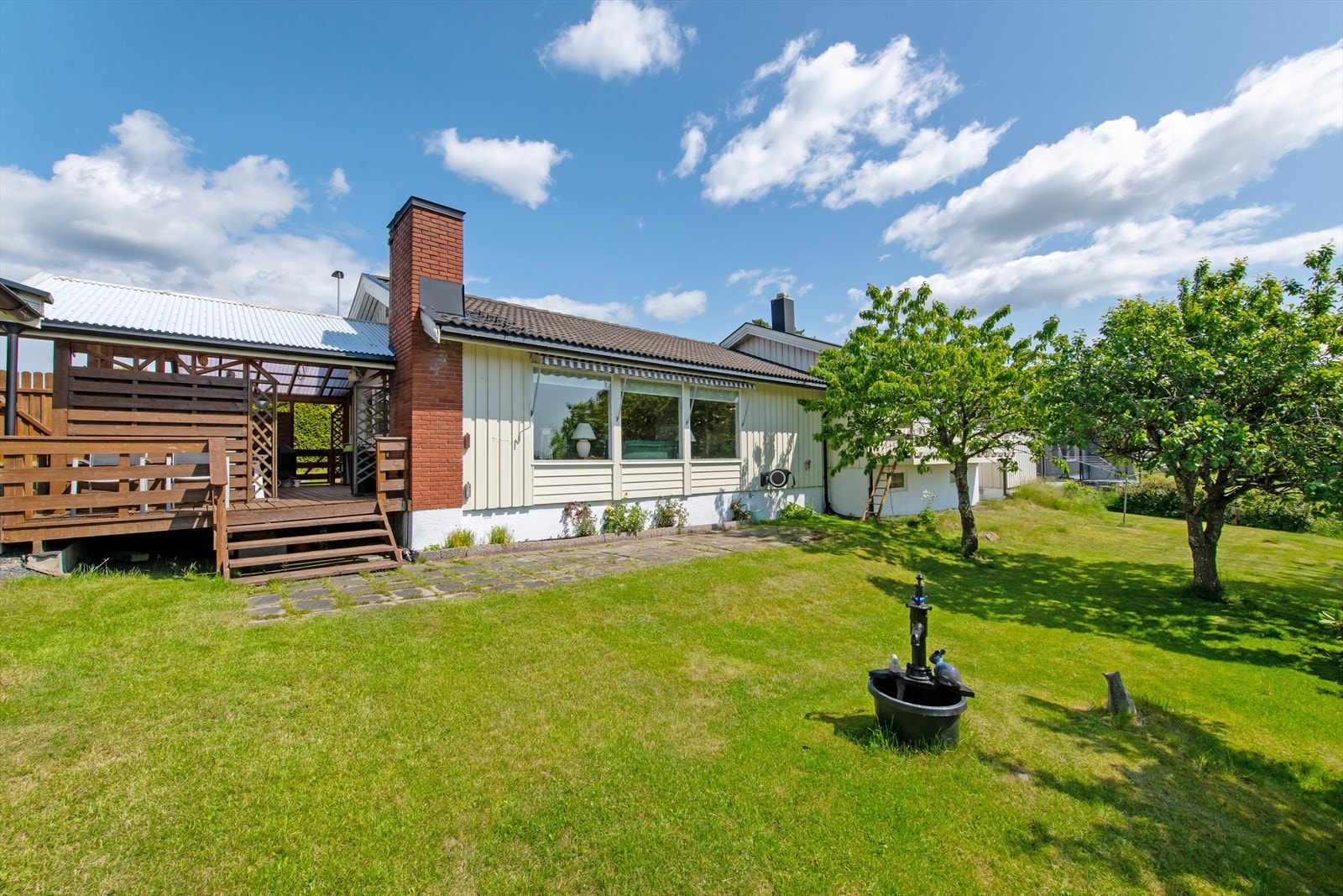 Utearealet er pent opparbeidet med gressplen, blomsterbed og trær. Galleribilde