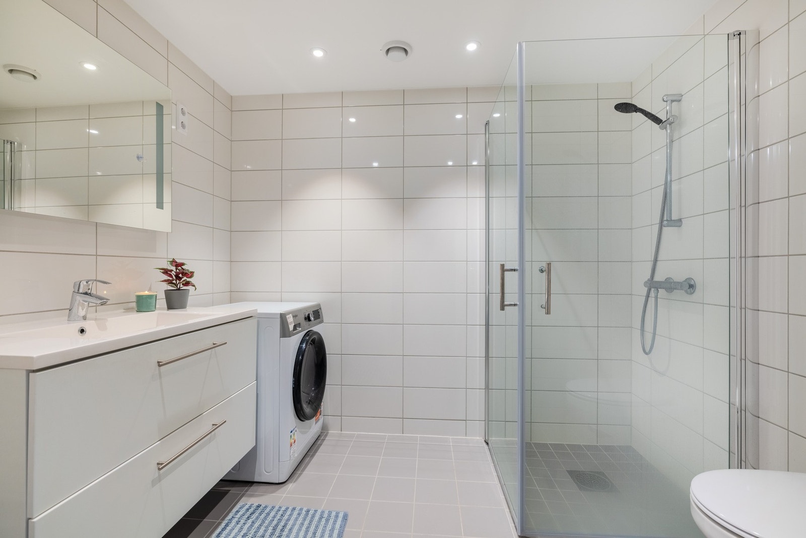 Badet har flislagt gulv, våtromsplater på veggene. Galleribilde