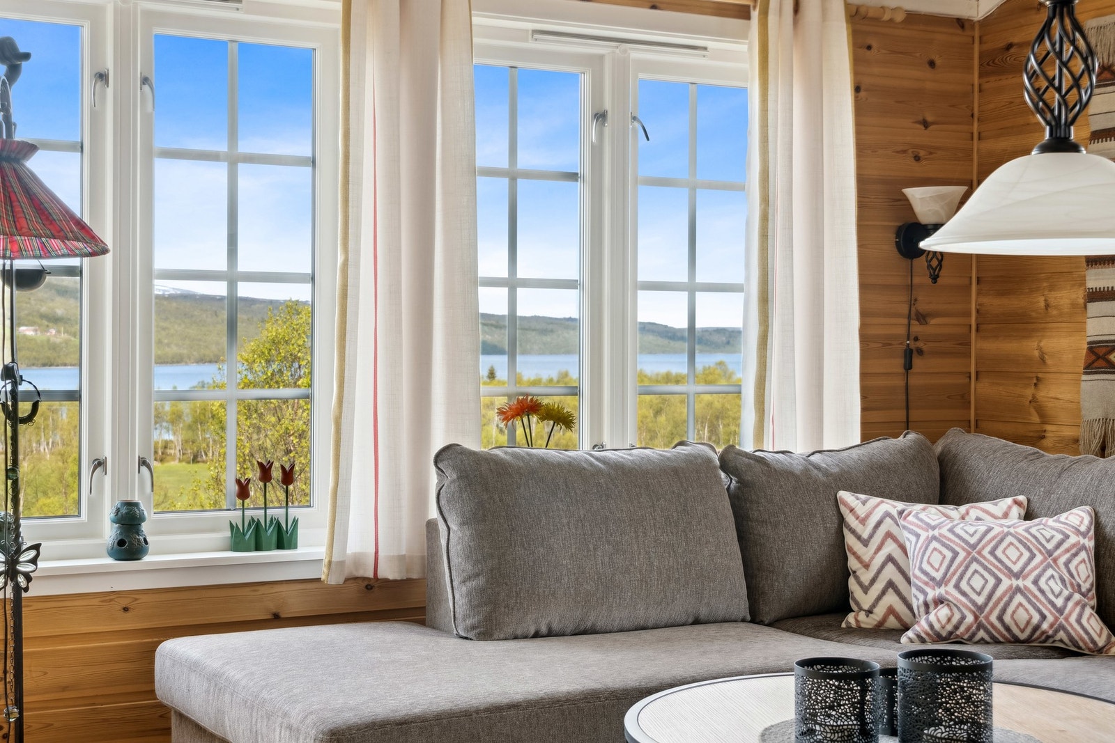 Fra stuen har du fantastisk utsikt over uteområde med sjø og fjell. Galleribilde