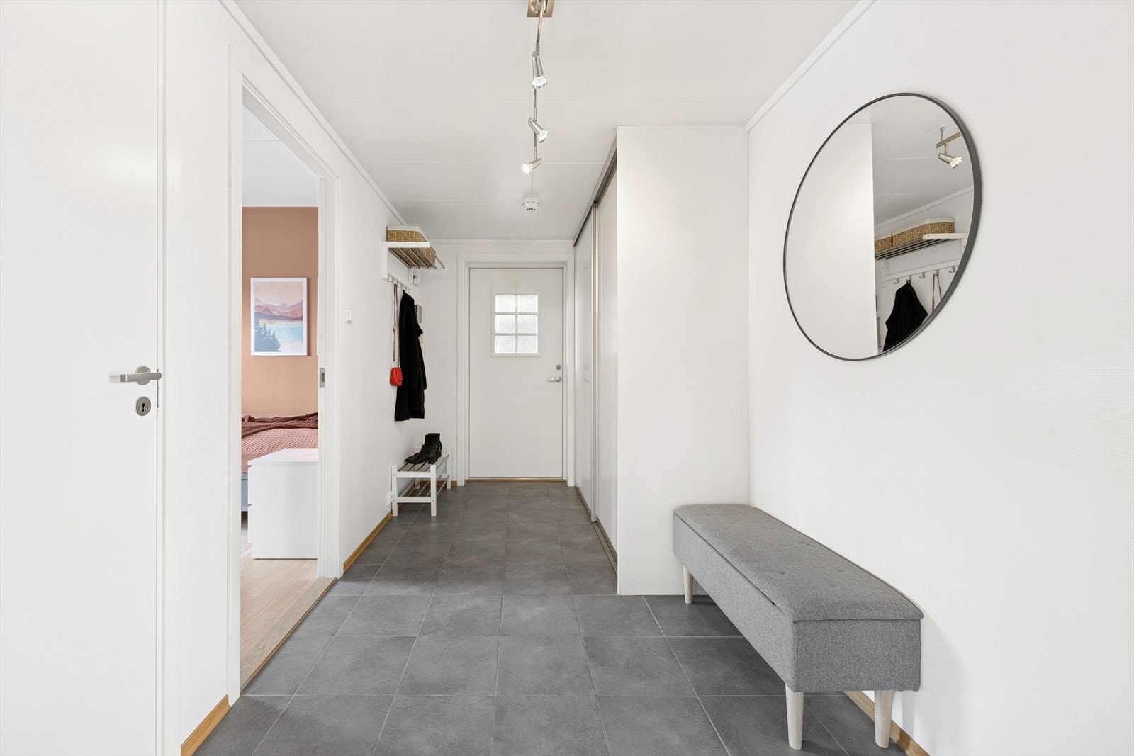 Entreen som ønsker det velkommen inn gir et godt førsteinntrykk av leiligheten med hvitmalte vegger og grå fliser med gulvvarme. Galleribilde